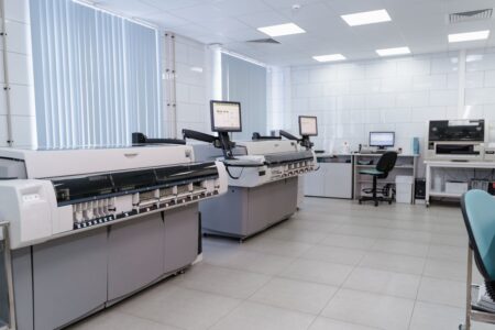 A technician configuring equipment in a remote test lab, with various devices and screens displaying testing software. The workspace is organized, showcasing best practices for remote testing setups.